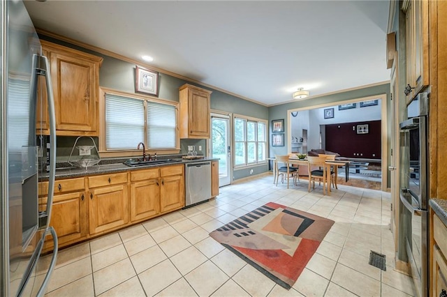 kitchen featuring light tile patterned floors, ornamental molding, appliances with stainless steel finishes, and a sink