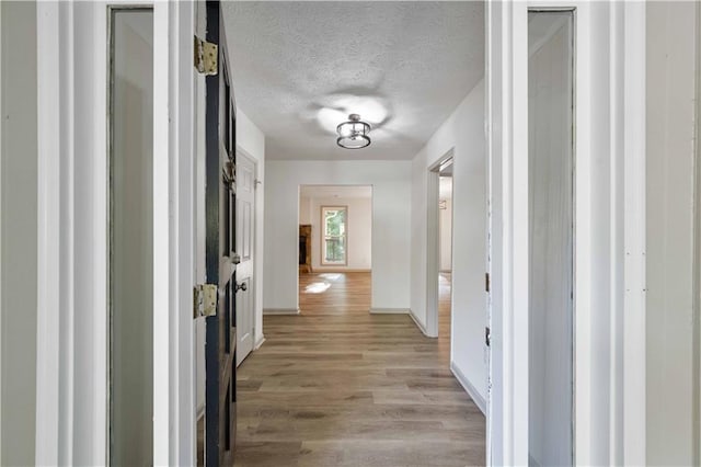 hall with light hardwood / wood-style flooring and a textured ceiling