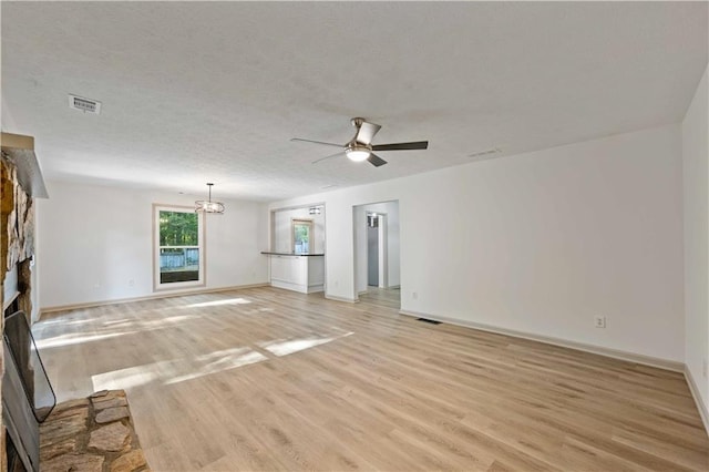 unfurnished room featuring a fireplace, ceiling fan with notable chandelier, and light hardwood / wood-style floors