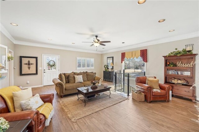 living room featuring a wealth of natural light, ornamental molding, and light wood-type flooring