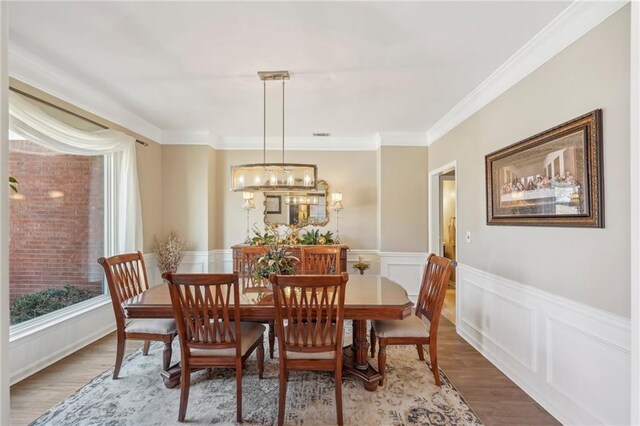 dining room featuring an inviting chandelier, wood-type flooring, and ornamental molding