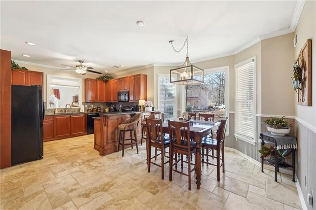 dining room with sink, ceiling fan with notable chandelier, and ornamental molding