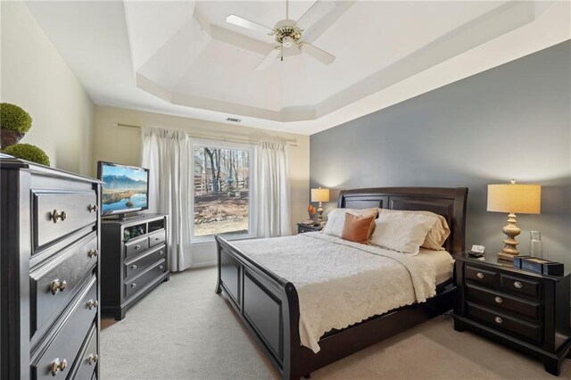 carpeted bedroom featuring a raised ceiling and ceiling fan