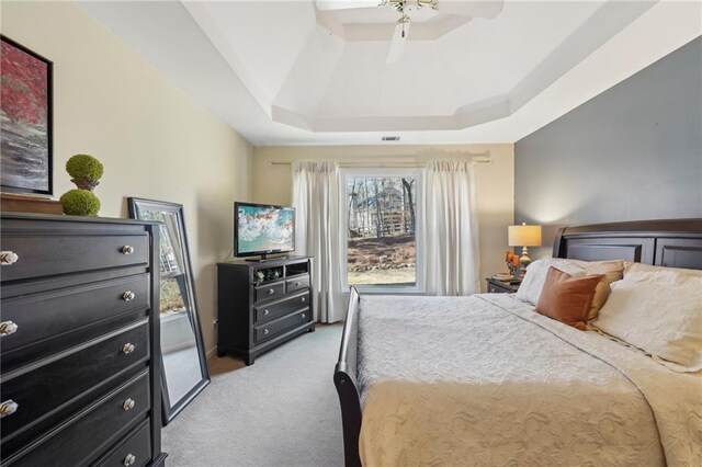 carpeted bedroom featuring ceiling fan and a tray ceiling