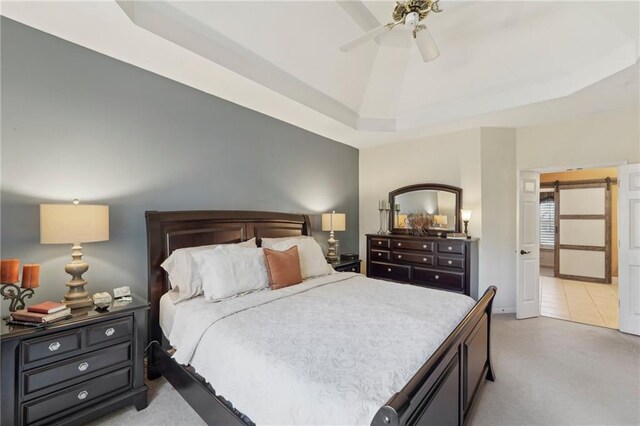 carpeted bedroom featuring a tray ceiling, vaulted ceiling, a barn door, and ceiling fan