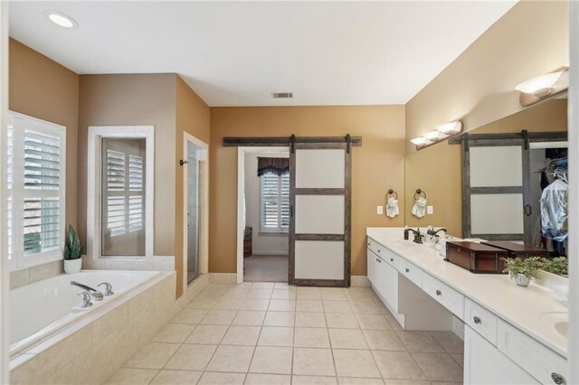 bathroom with plenty of natural light, independent shower and bath, tile patterned flooring, and vanity