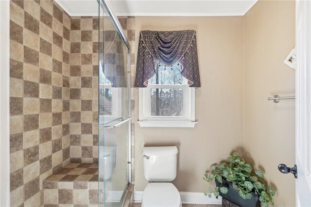 bathroom featuring a shower with door and toilet