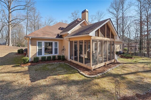 rear view of house with a yard and a sunroom