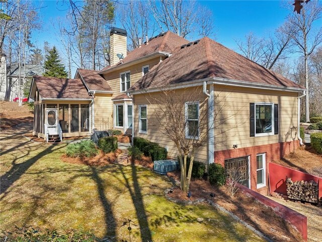 rear view of house with a yard and a sunroom