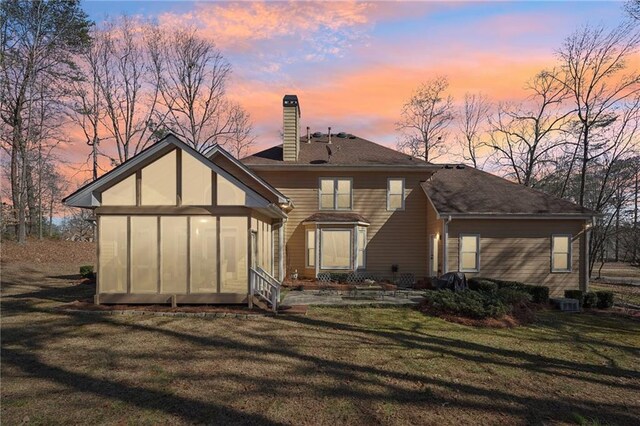 back house at dusk featuring a yard