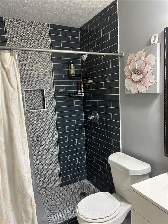 6658 Ramsgate Way, Norcross, GA 30093 - full bath with a shower stall, toilet, vanity, and a textured ceiling
