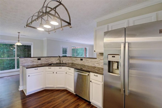 kitchen with sink, dark stone counters, pendant lighting, stainless steel appliances, and white cabinets