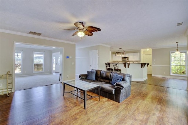 living room with crown molding, plenty of natural light, ceiling fan, and light hardwood / wood-style flooring