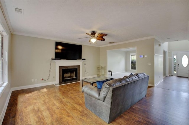 living room featuring a healthy amount of sunlight, wood-type flooring, and ornamental molding