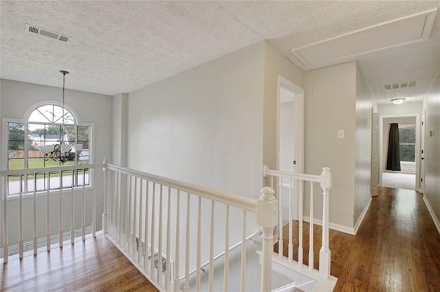 hall with hardwood / wood-style flooring, an inviting chandelier, and a textured ceiling