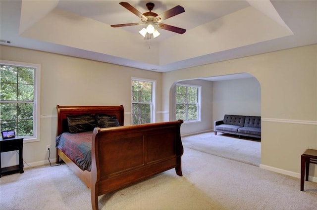 bedroom featuring light colored carpet, ceiling fan, and a tray ceiling