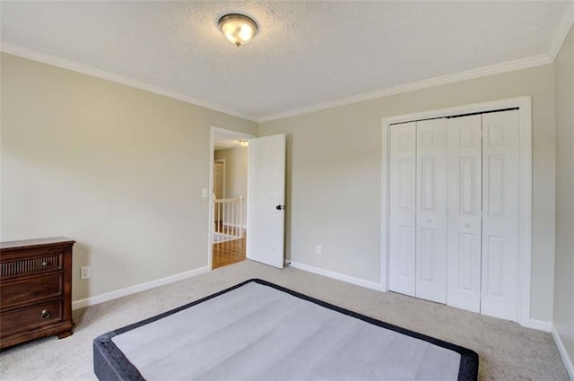 unfurnished bedroom featuring ornamental molding, light colored carpet, a textured ceiling, and a closet