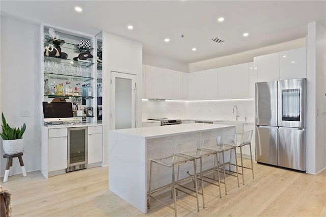 kitchen with beverage cooler, light wood-style flooring, smart refrigerator, white cabinetry, and a center island