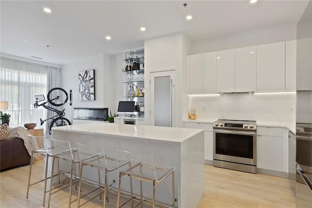 kitchen featuring a breakfast bar, white cabinets, and stainless steel electric range