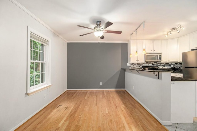 1445 Monroe Dr NE Unit F10, Atlanta, GA 30324 - kitchen featuring stainless steel microwave, dark countertops, white cabinets, decorative backsplash, and ornamental molding
