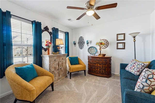 living area featuring light carpet, ceiling fan, visible vents, and baseboards