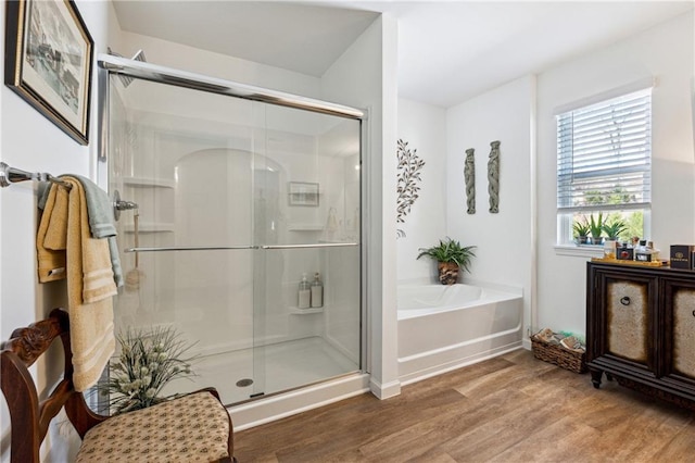 bathroom featuring a garden tub, a shower stall, and wood finished floors