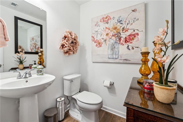 bathroom with baseboards, visible vents, toilet, wood finished floors, and a sink