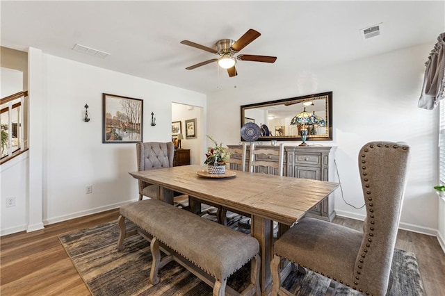 dining space with dark wood-type flooring, a ceiling fan, visible vents, and baseboards