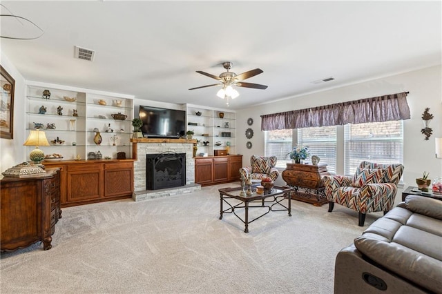 living area featuring a ceiling fan, light colored carpet, visible vents, and a stone fireplace