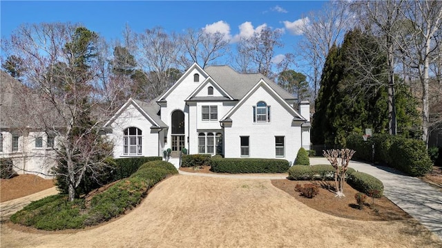 view of front of home featuring driveway, brick siding, and a chimney