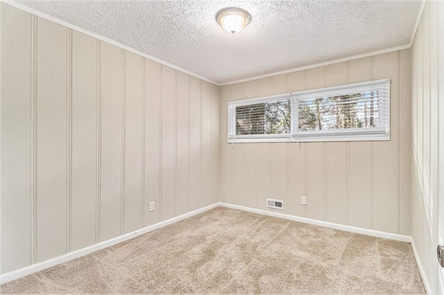 empty room with a textured ceiling, carpet flooring, visible vents, and crown molding