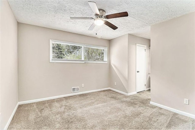 spare room featuring carpet, visible vents, ceiling fan, a textured ceiling, and baseboards