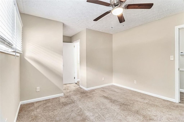 spare room with a textured ceiling, carpet flooring, a ceiling fan, and baseboards