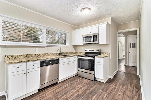 kitchen featuring dark wood-style floors, appliances with stainless steel finishes, light stone counters, white cabinetry, and a sink