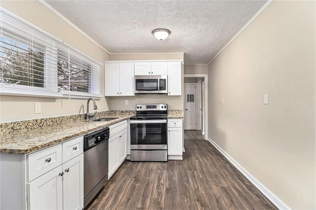 kitchen with stainless steel appliances, a sink, white cabinets, dark wood-style floors, and crown molding