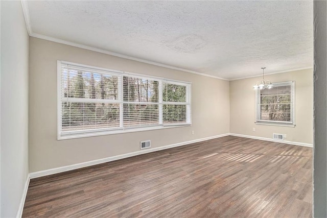 spare room featuring ornamental molding, wood finished floors, visible vents, and a notable chandelier