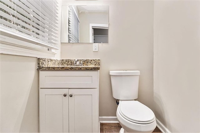 bathroom featuring baseboards, vanity, and toilet