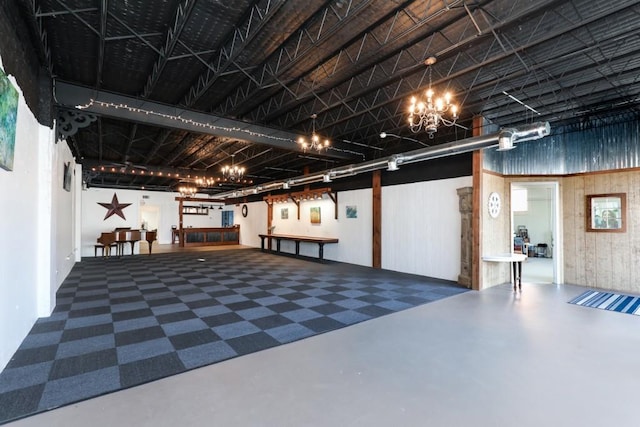 basement featuring an inviting chandelier and wood walls