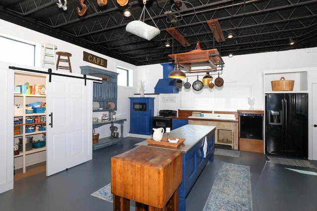 kitchen with blue cabinets, a barn door, black appliances, and hanging light fixtures