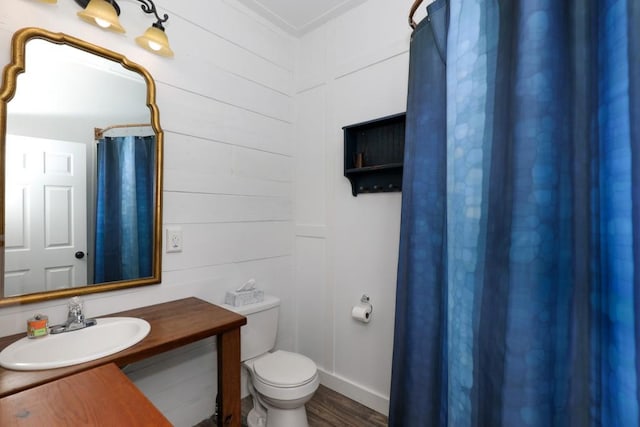 bathroom with hardwood / wood-style floors, wood walls, vanity, and toilet