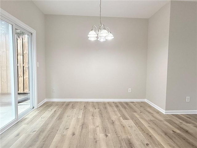 spare room with a chandelier and light wood-type flooring