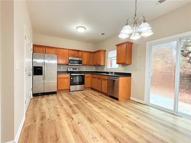 kitchen with appliances with stainless steel finishes, sink, a chandelier, light hardwood / wood-style floors, and hanging light fixtures