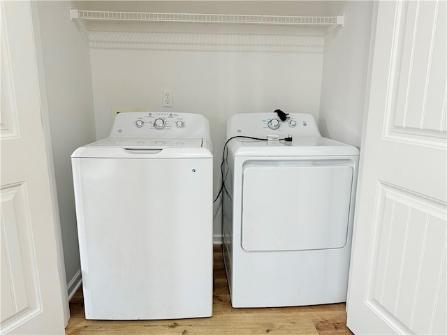 laundry room with washing machine and dryer and light hardwood / wood-style floors