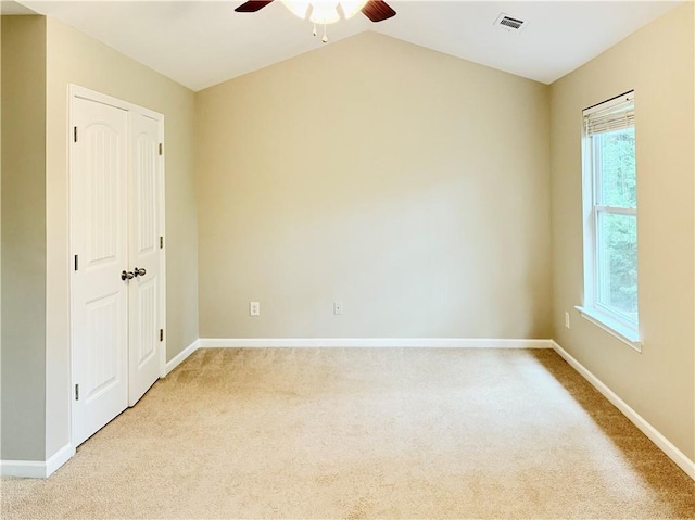 carpeted spare room featuring ceiling fan and lofted ceiling