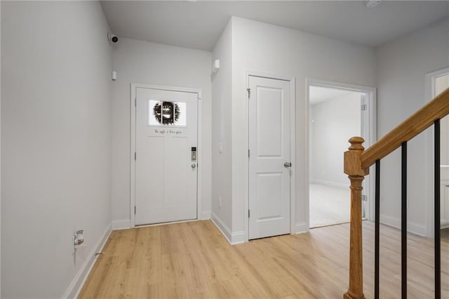 entryway featuring stairs, light wood-style flooring, and baseboards