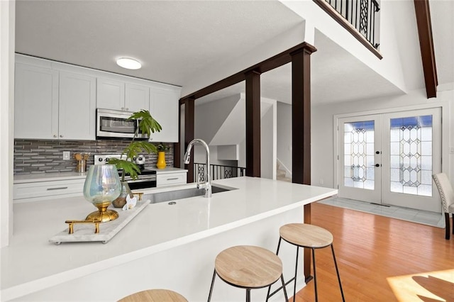 kitchen featuring a breakfast bar, light wood finished floors, stainless steel appliances, backsplash, and a sink