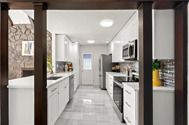 kitchen with white cabinets, stainless steel appliances, a sink, and light countertops