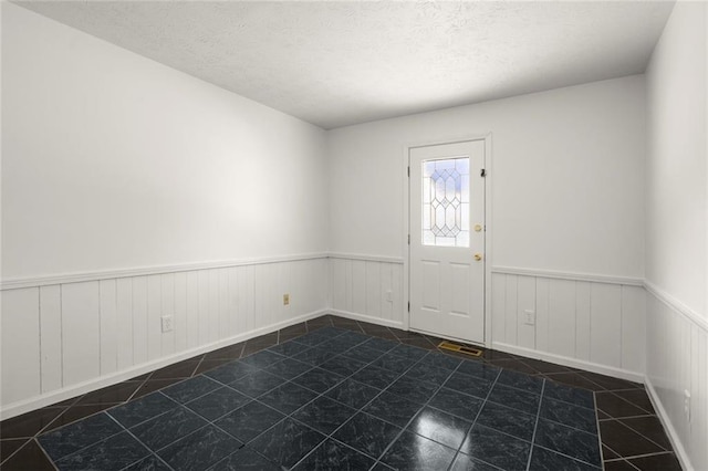 foyer entrance featuring wainscoting and a textured ceiling