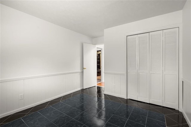 unfurnished bedroom with a closet, wainscoting, and tile patterned floors