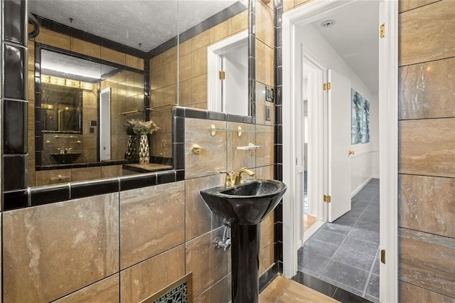 bathroom with tile patterned flooring, a textured ceiling, and tile walls